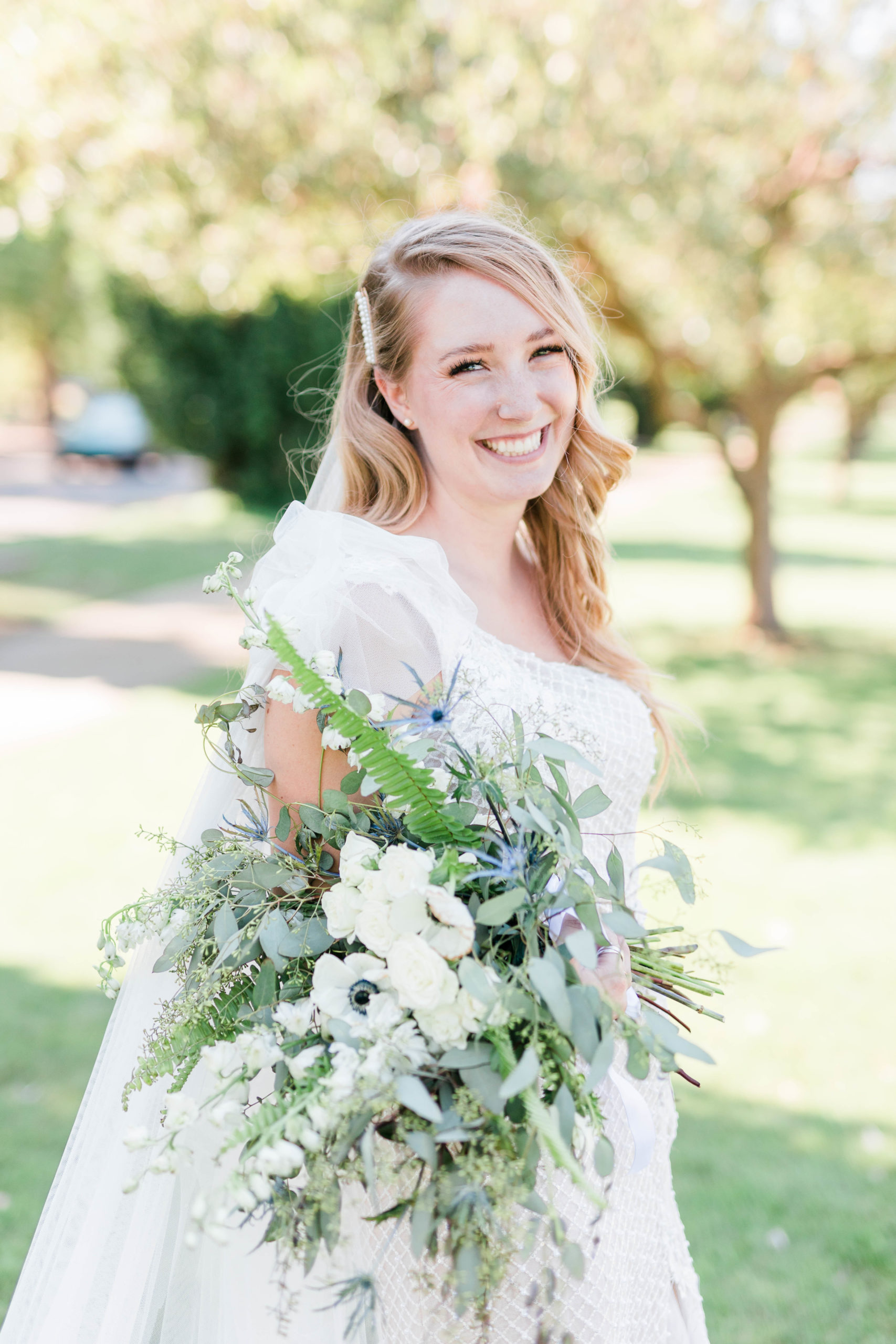 Boise outdoor wedding with bride holding her white and blue bouquet and smiling at the camera