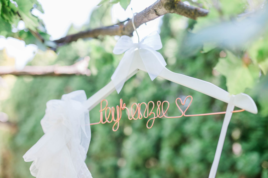 wedding dress hanger with brides new last name on it in the wire hanging from a tree for a Boise wedding 