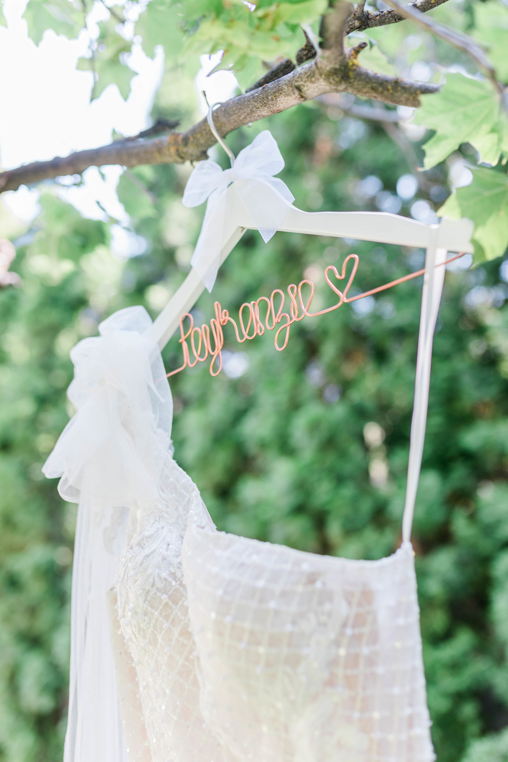 wedding dress hanging from a tree on a custom wood hanger