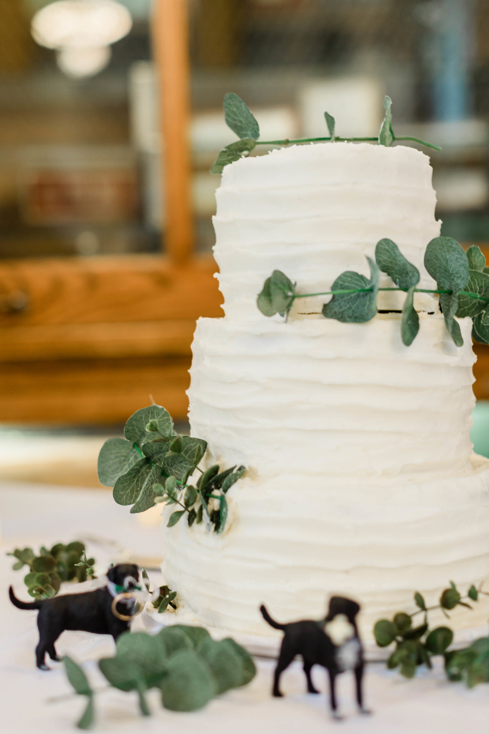 white wedding cake with green details in the live greenery 