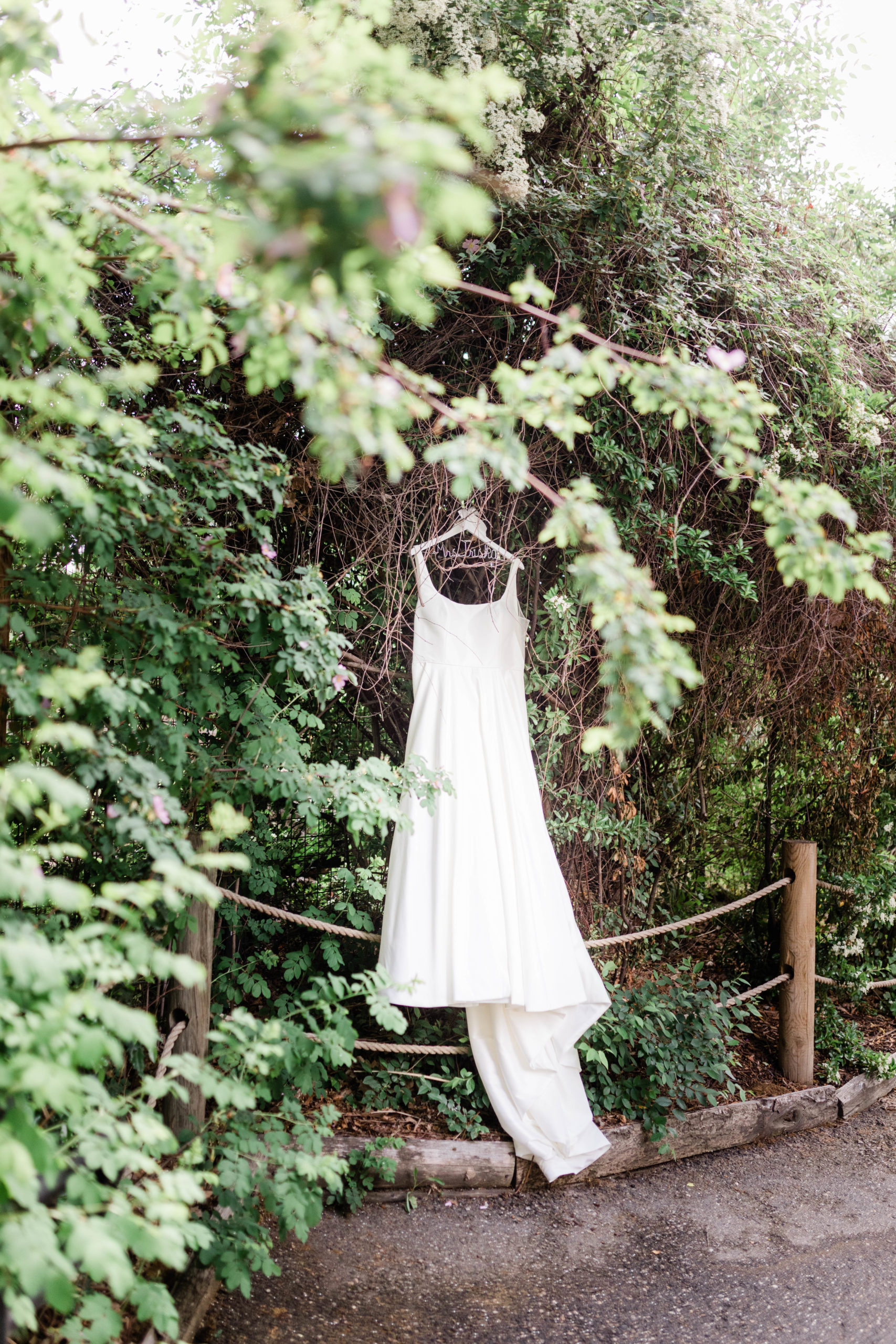 wedding dress hanging in greenery while bride got ready for colorful boise zoo wedding