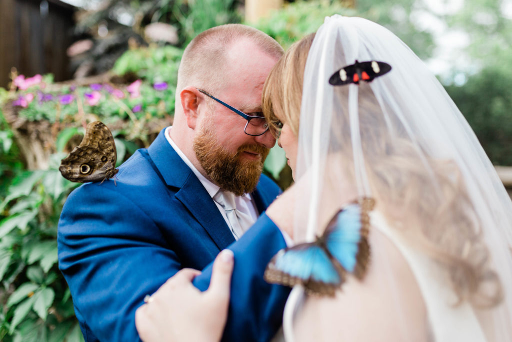 bride and groom embracing with butterflies surrounding them at boise zoo wedding