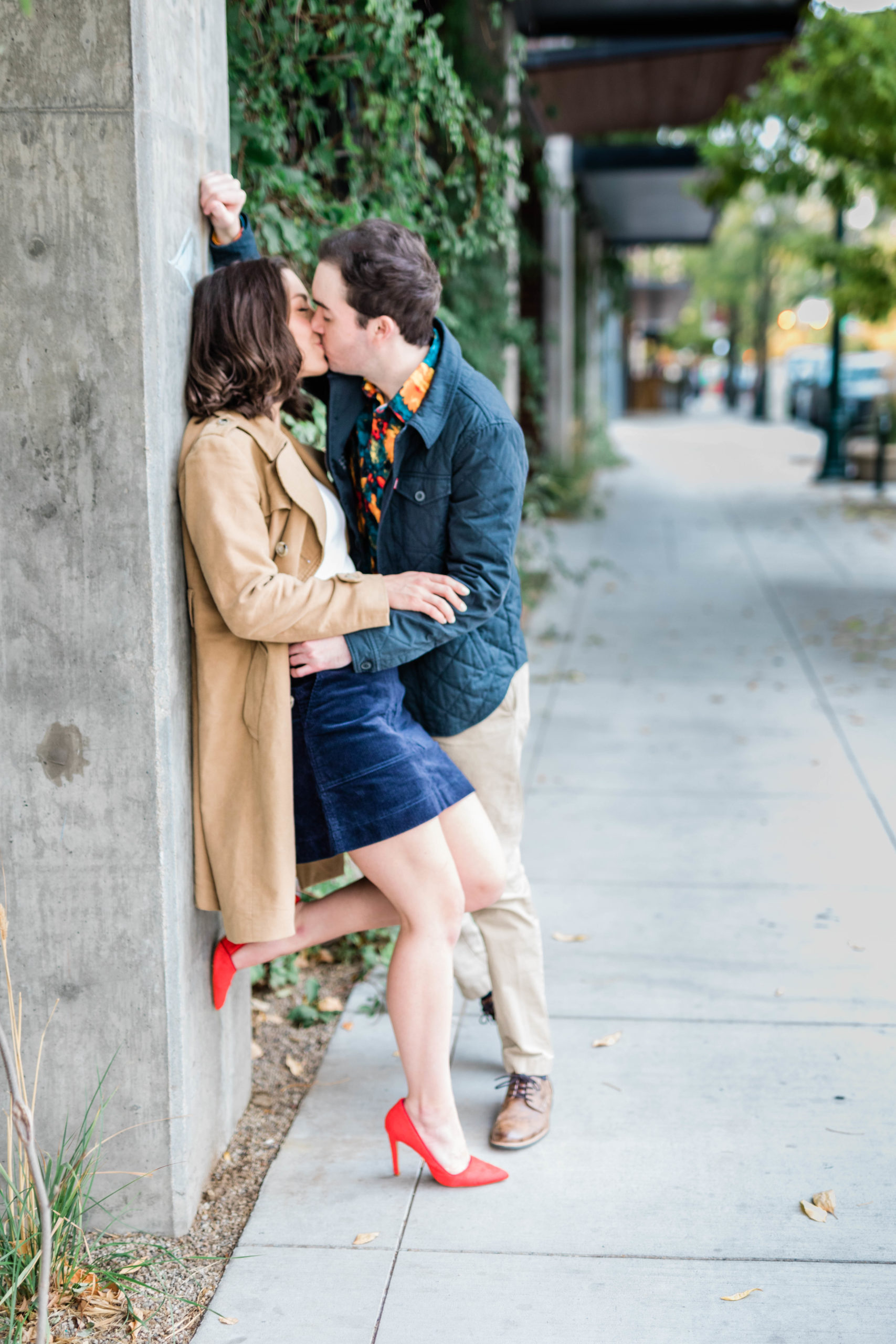 Boise wedding photographer captures man and woman kissing against wall during downtown boise engagements