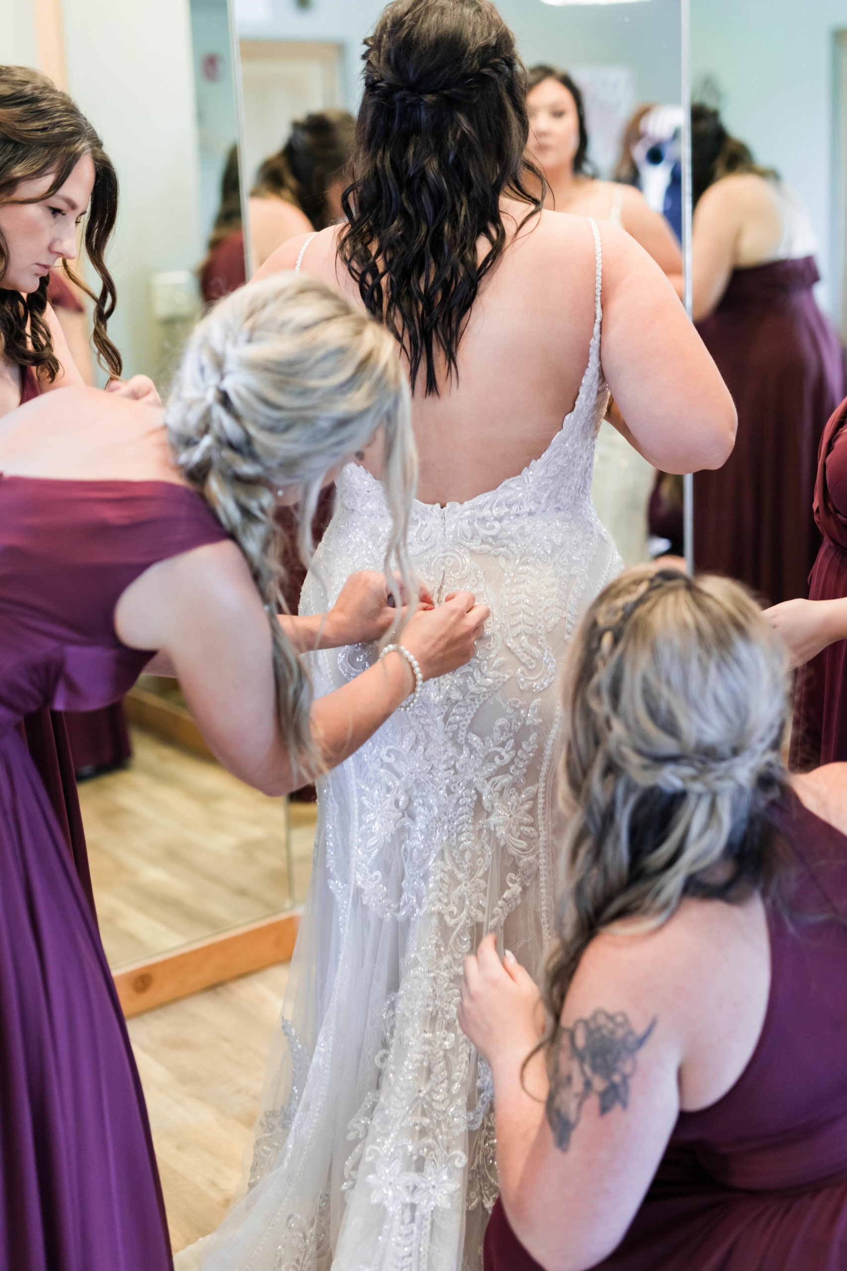 bride getting buttoned into wedding dress