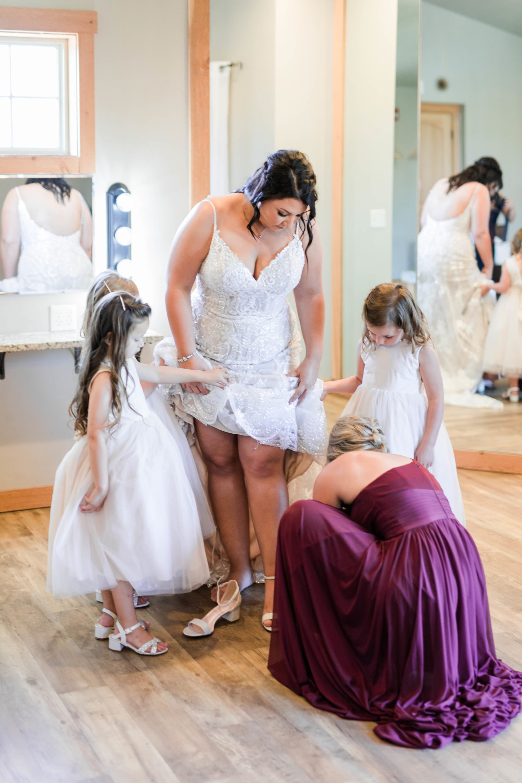 bridesmaid putting on bride's shoes before still water hollow wedding
