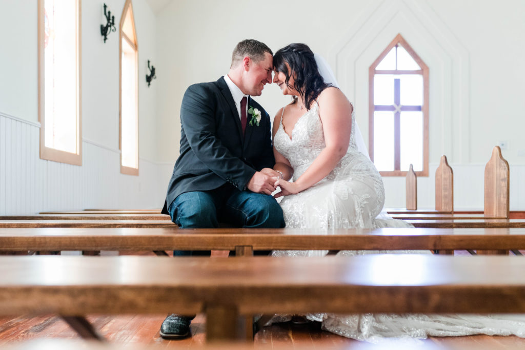 bride and groom sitting in pew before wedding ceremony