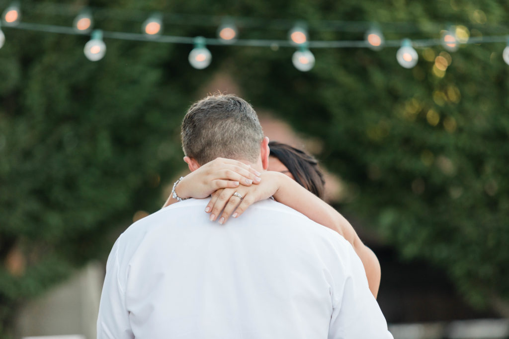 close up of bride's hands wrapped around groom's neck