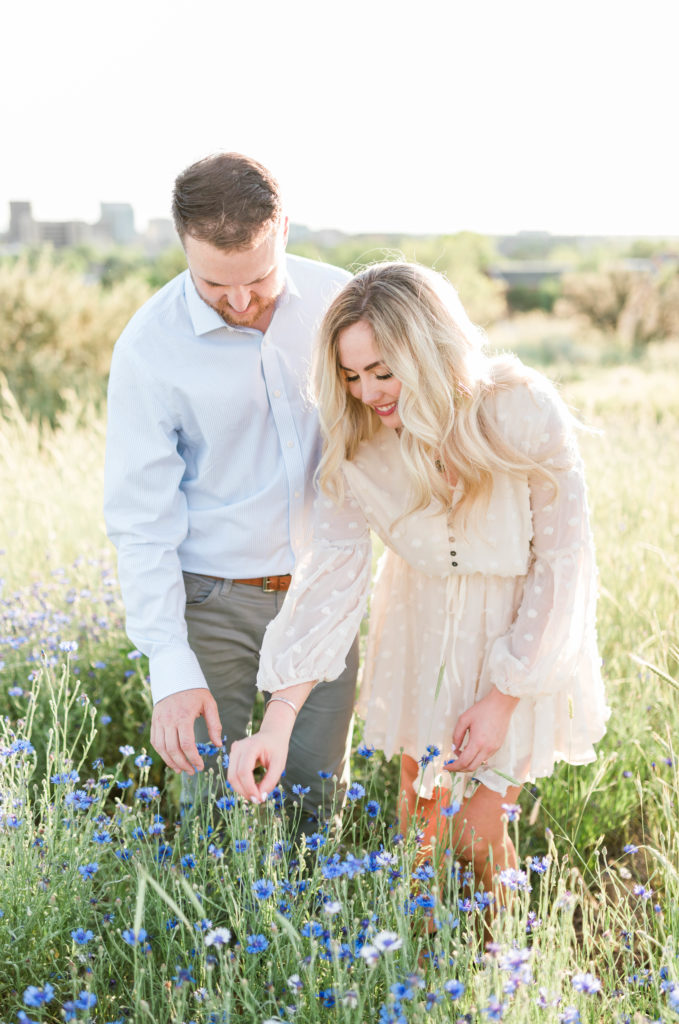 couple walking through field of grass looking at wildflowers