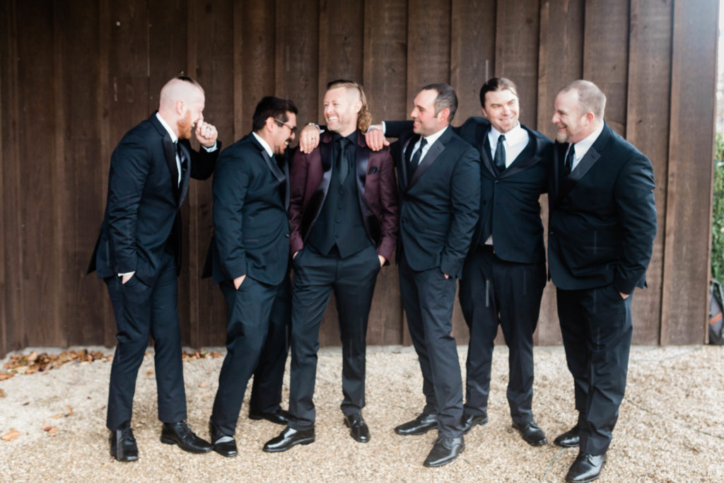 Boise wedding photographer captures groom wearing maroon suit jacket standing with groomsmen