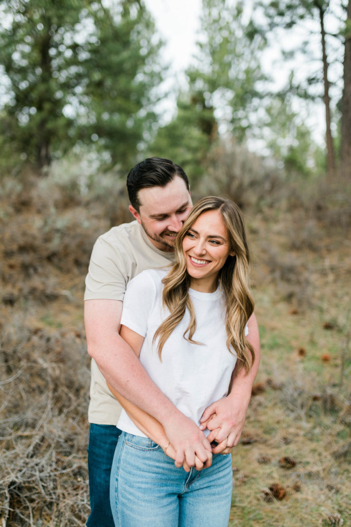 Idaho wedding photographer captures man hugging woman from behind during outdoor engagement session