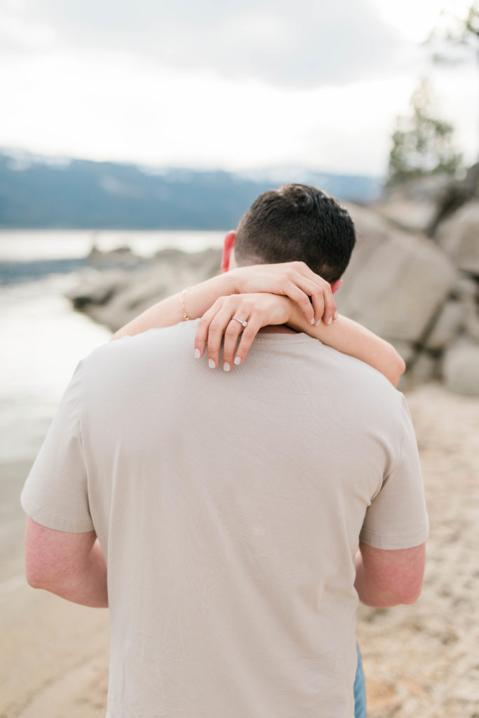 Boise wedding photographers capture woman's hands wrapped around man's neck during cascade lake engagement session