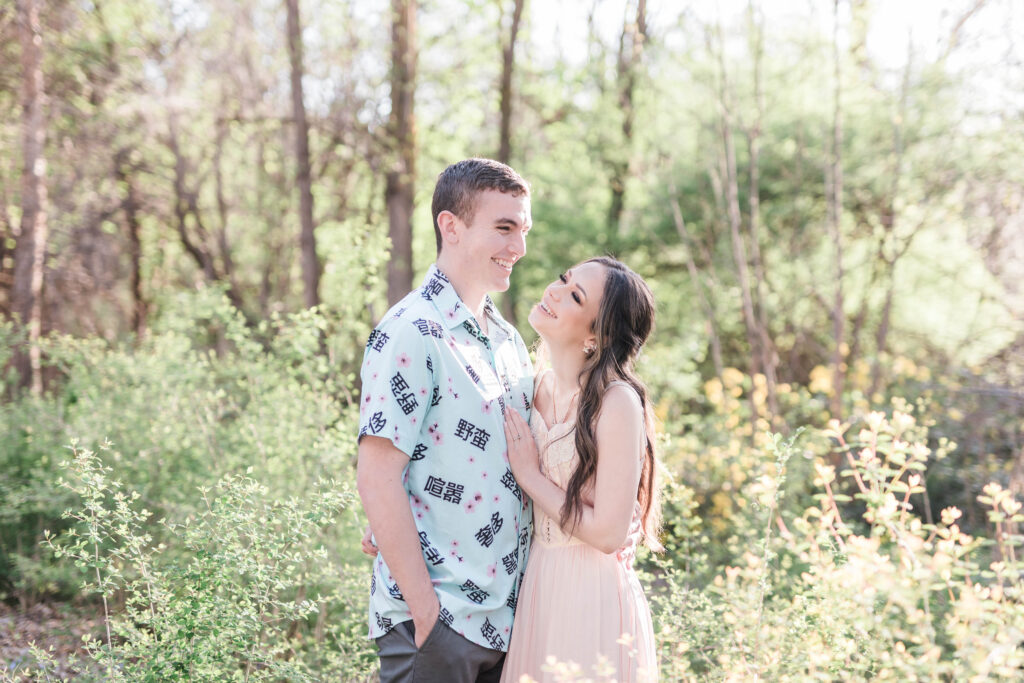 Boise wedding photographer captures couple embracing while woman wears pink dress and man wearing blue patterned shirt