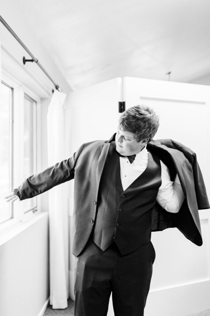 Boise wedding photographers capture groom getting coat on