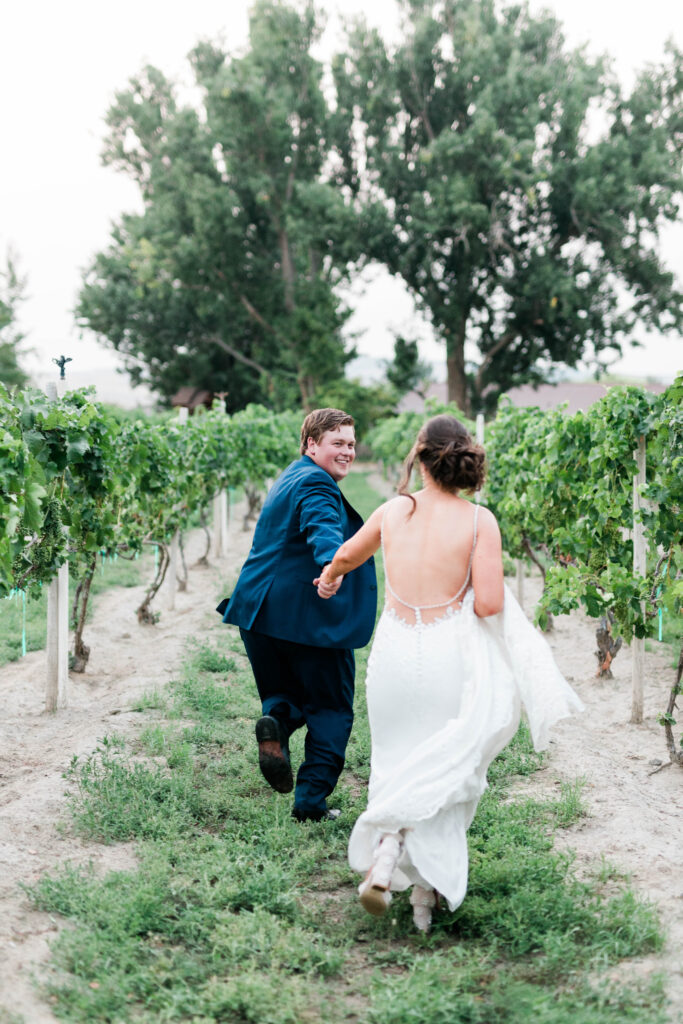 Boise wedding photographers capture bride and groom running through vineyard