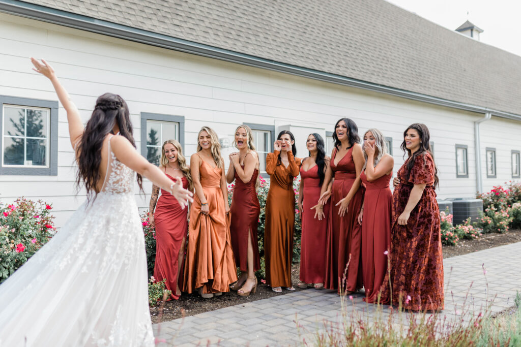 Boise wedding photographer captures bride showing bridesmaids her wedding dress