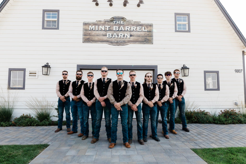 Boise wedding photographer captures groomsmen standing with groom wearing black vests
