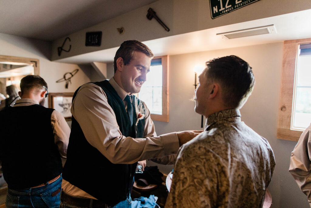 Boise wedding photographer captures groom helping groomsmen getting ready