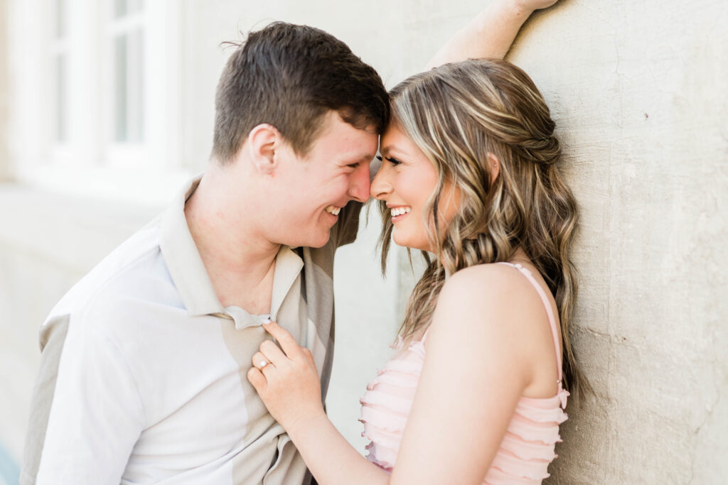 Boise wedding photographer captures couple leaning against wall wearing pink shirt and neutrals